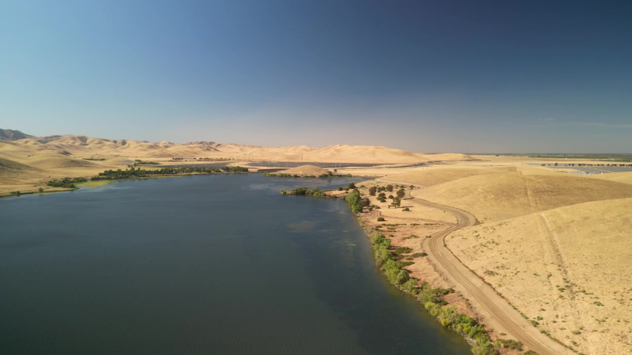 Havadan drone, sakin San Luis Rezervuarı üzerinde süzülerek geniş suları ve engebeli tepeleri görüntülüyor.