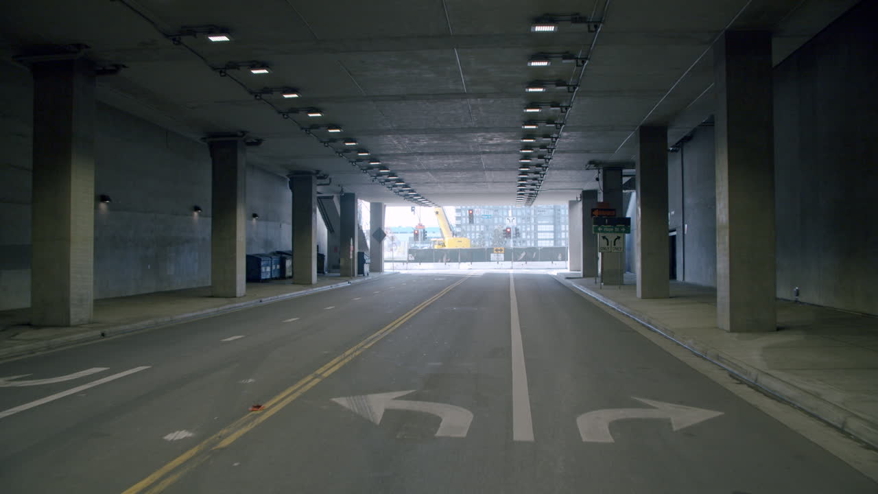 Empty Road Tunnel with Concrete Pillars and Distant Construction Site