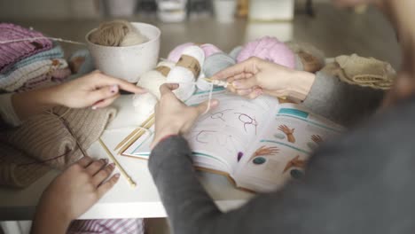 mother teaches daughter knitting needles. woman hands knitting woolen thread