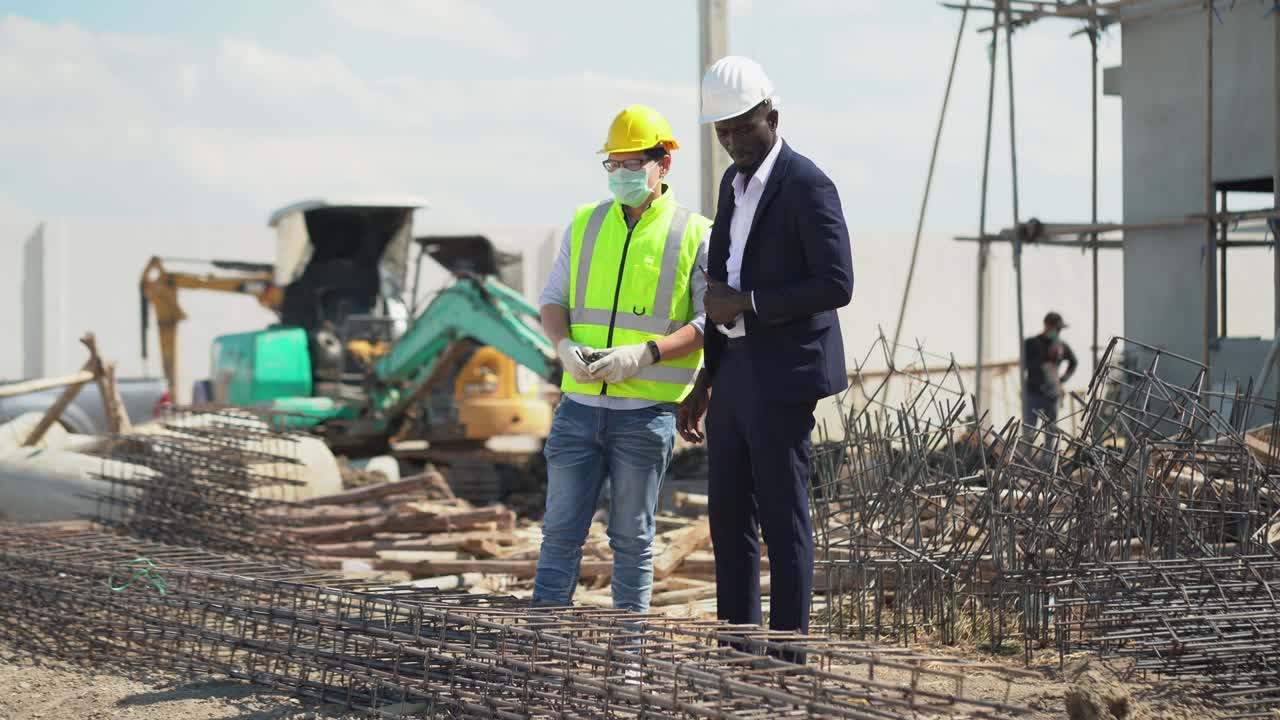 asian foreman and african american architect  checking steel structure outdoors on construction site at village . contractor worker Inspection and correction rebar steel cage . quality control