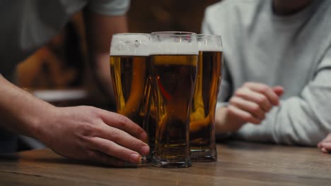 primer plano de un hombre irreconocible trayendo vasos de cerveza para amigos