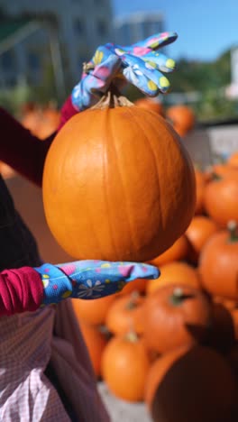 persona que sostiene una gran calabaza naranja