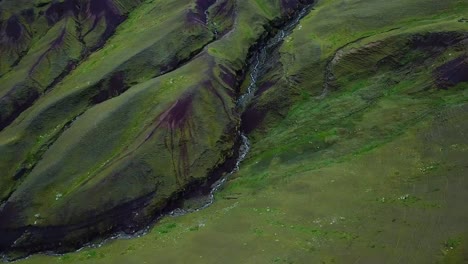 Aerial,-tilt-up,-drone-shot,-over-green-hills-and-geographical-formations,-in-the-Andes-mountains,-on-a-overcast-day,-near-Cuzco,-in-Peru