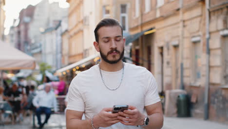tourist traveler young man guy using looking smartphone search a way on map in mobile navigator app