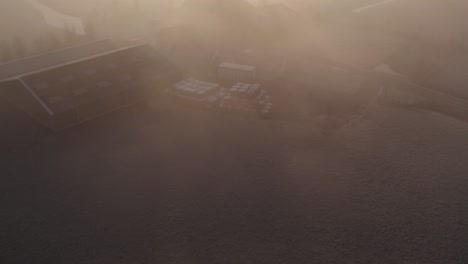 Dutch-farmhouse-during-a-magical-foggy-morning-with-dense-mist,-aerial