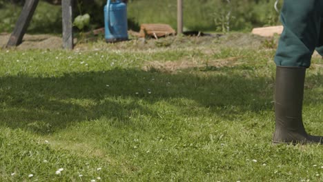 Farmer-man-walking-with-blue-watering-can-in-his-private-garden-in-slow-motion