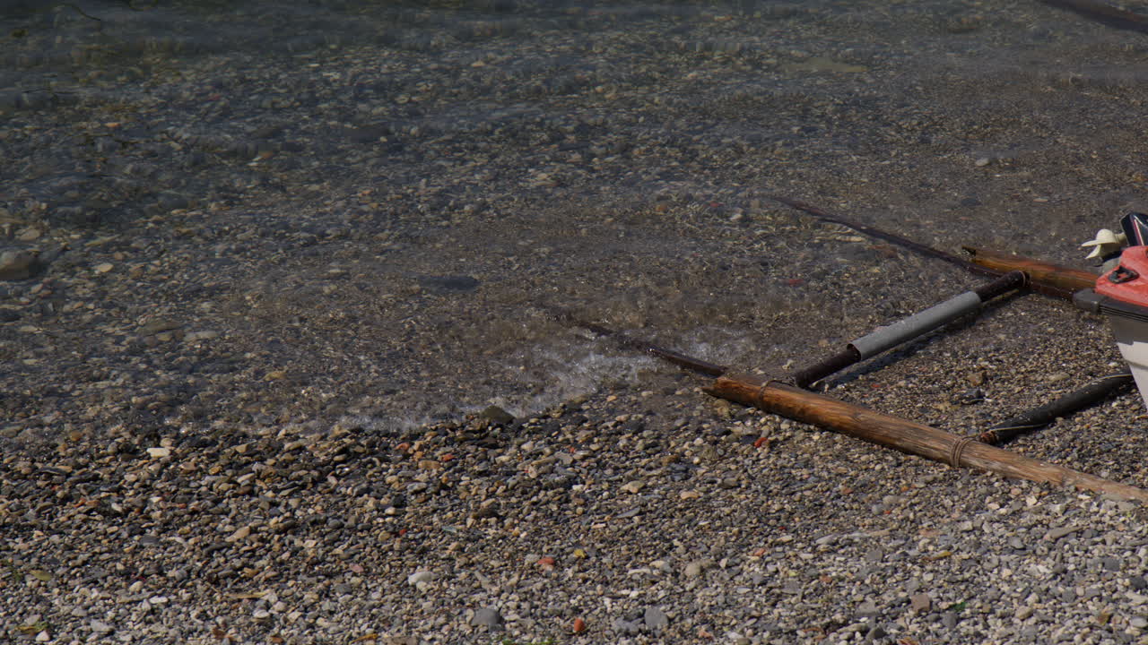 Pebbled Shores Of A Peaceful Lake With Anchored Boat. Close-up Shot