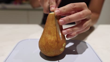 person slicing a pear in the kitchen