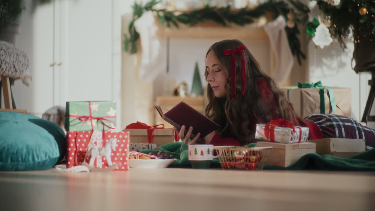 집에서 크리스마스 동안 바닥에서 책을 읽는 젊은 여성