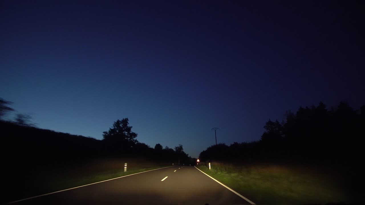 una toma pov conduciendo por un camino rural de noche