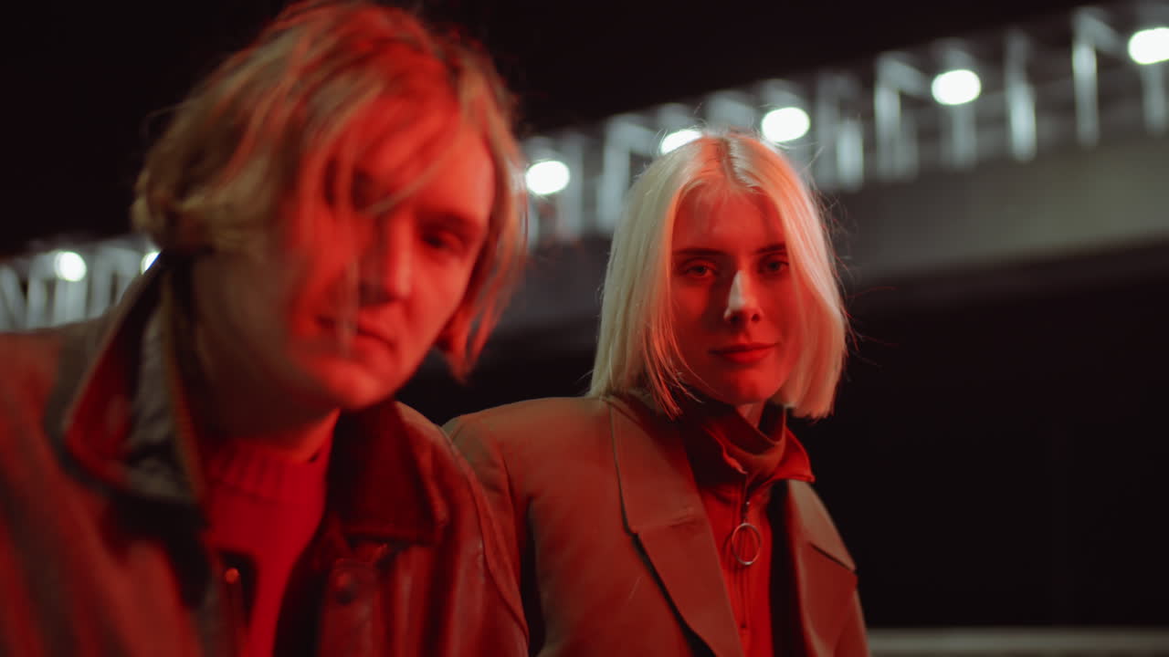 젊은 남자 와 여자 가 밤 에 야외 에서 카메라 를 위해 포즈 를 취하고 있다