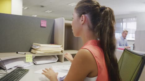 Caucasian-businesswoman-using-computer-and-walking-with-documents-in-office