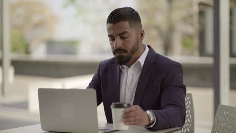 Un-Hombre-De-Negocios-Serio-Trabajando-Con-Una-Computadora-Portátil-En-La-Cafetería