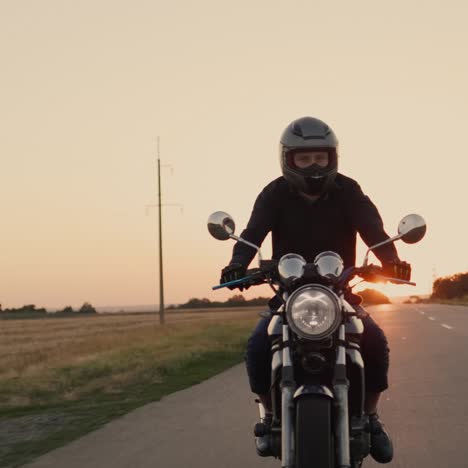 motociclista em uma jaqueta preta cavalga ao pôr do sol