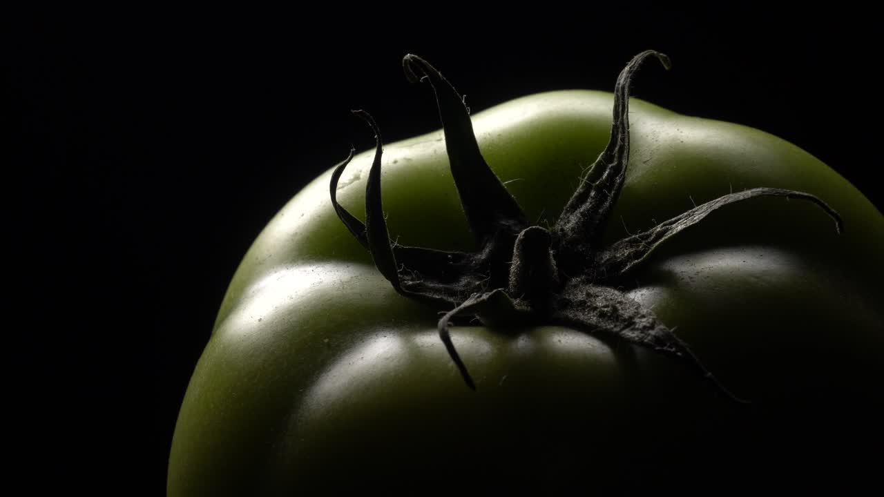 검은 바탕에 회전하는 초록색 토마토.