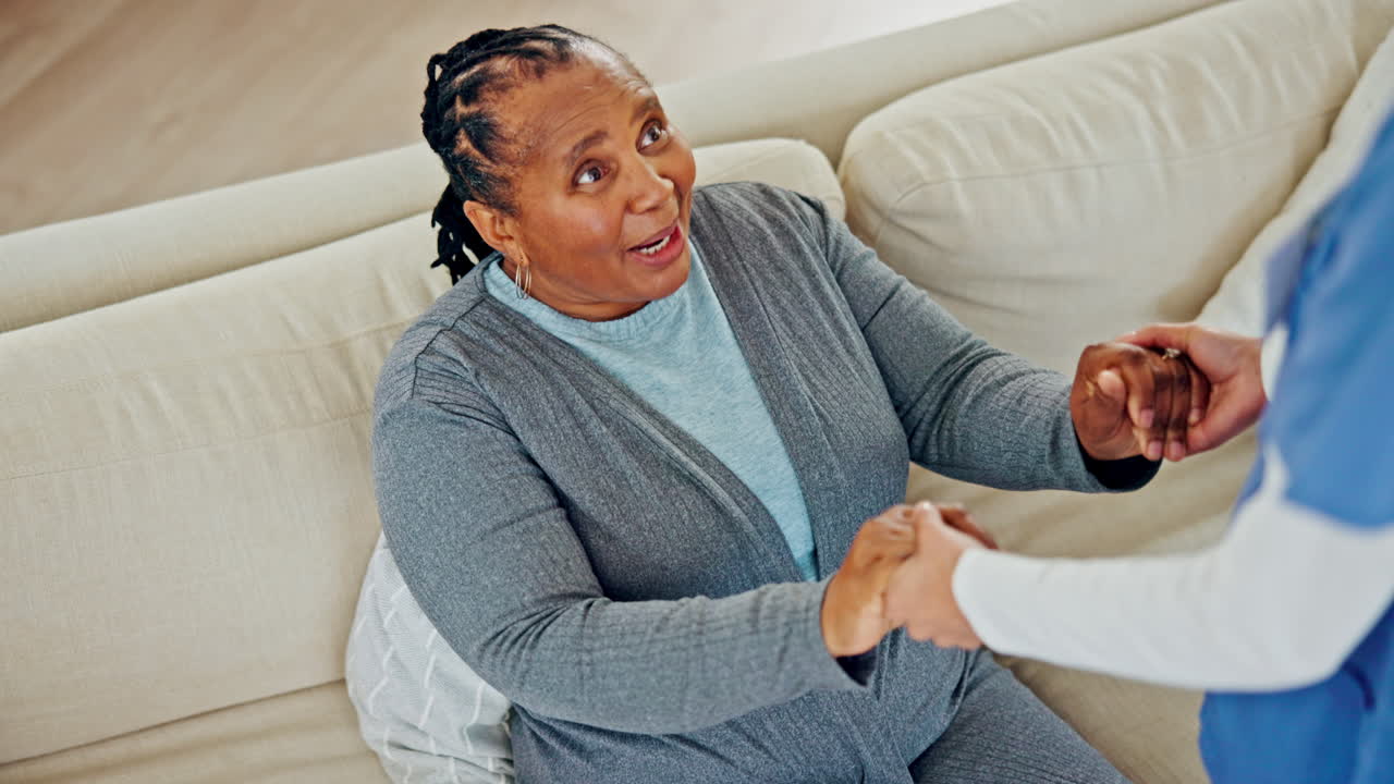 Black woman, senior and holding hands with nurse