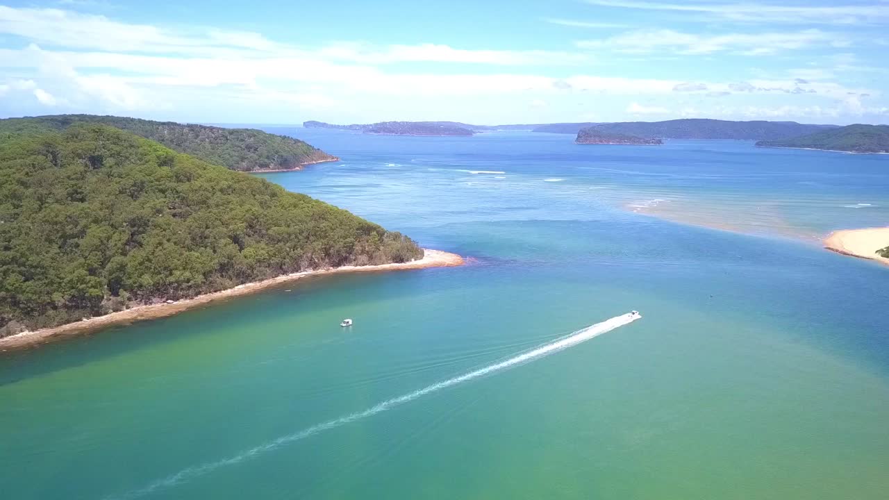 Aerial view tropical paradise beach turquoise water and white sand with speed boat crossing. Slow decending drone shot.