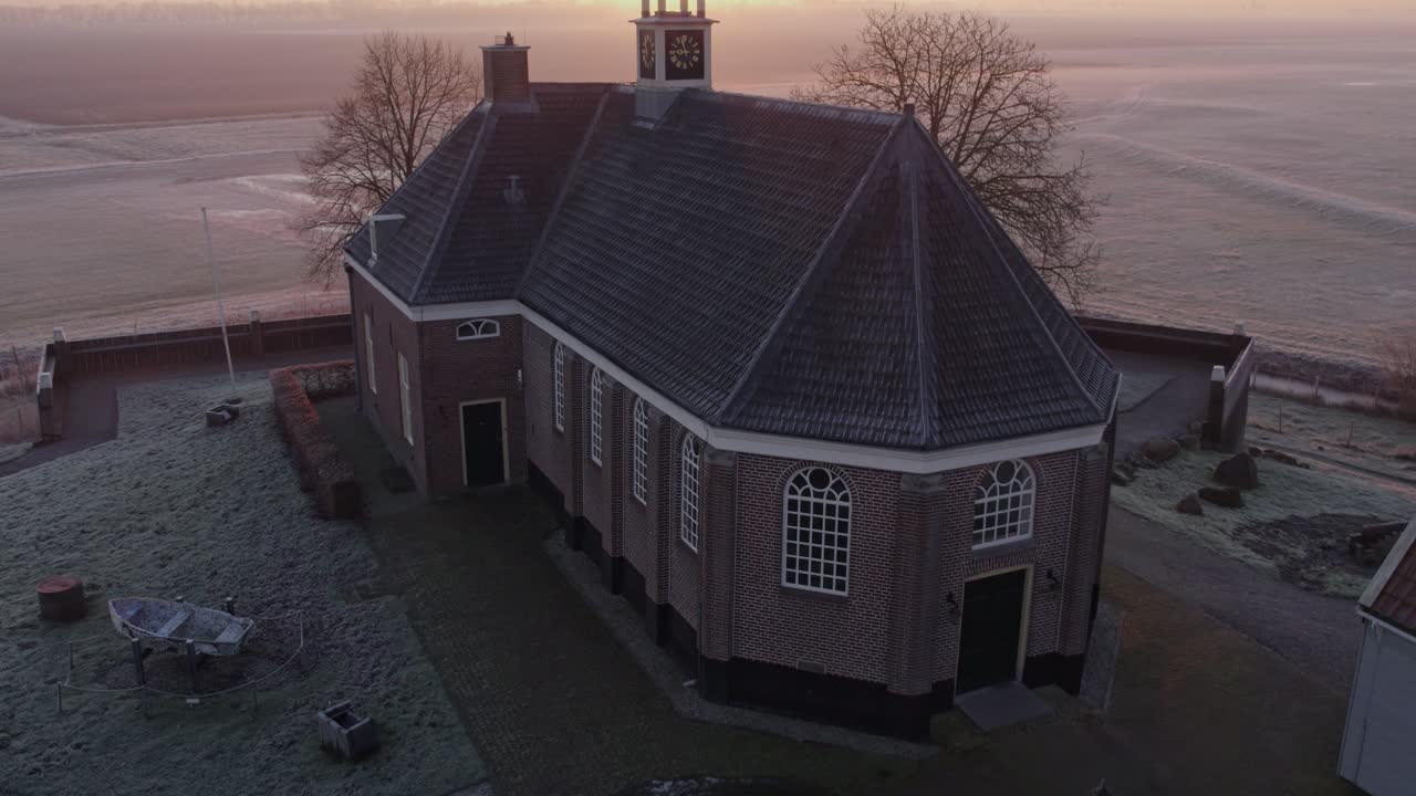 Golden sunrise over Schokland village, church, and houses, aerial perspective