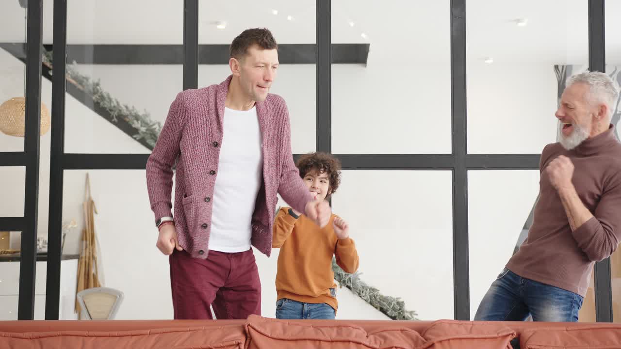 la familia gay se divierte juntos bailando a la música detrás del sofá.