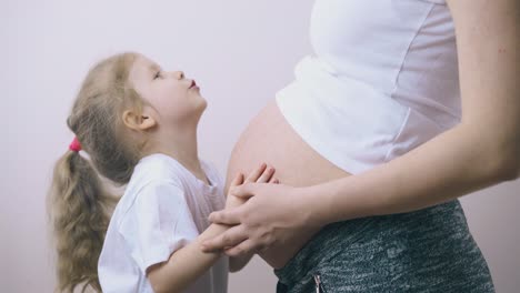 cute child talks to pregnant mother hugging large belly