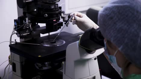 over the shoulder, camera moves slowly, showing a person operating a microscope