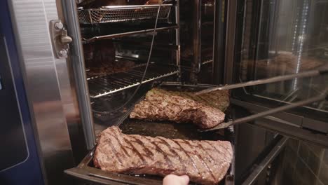 chef puts grilled venison meat pieces inside meat baking oven