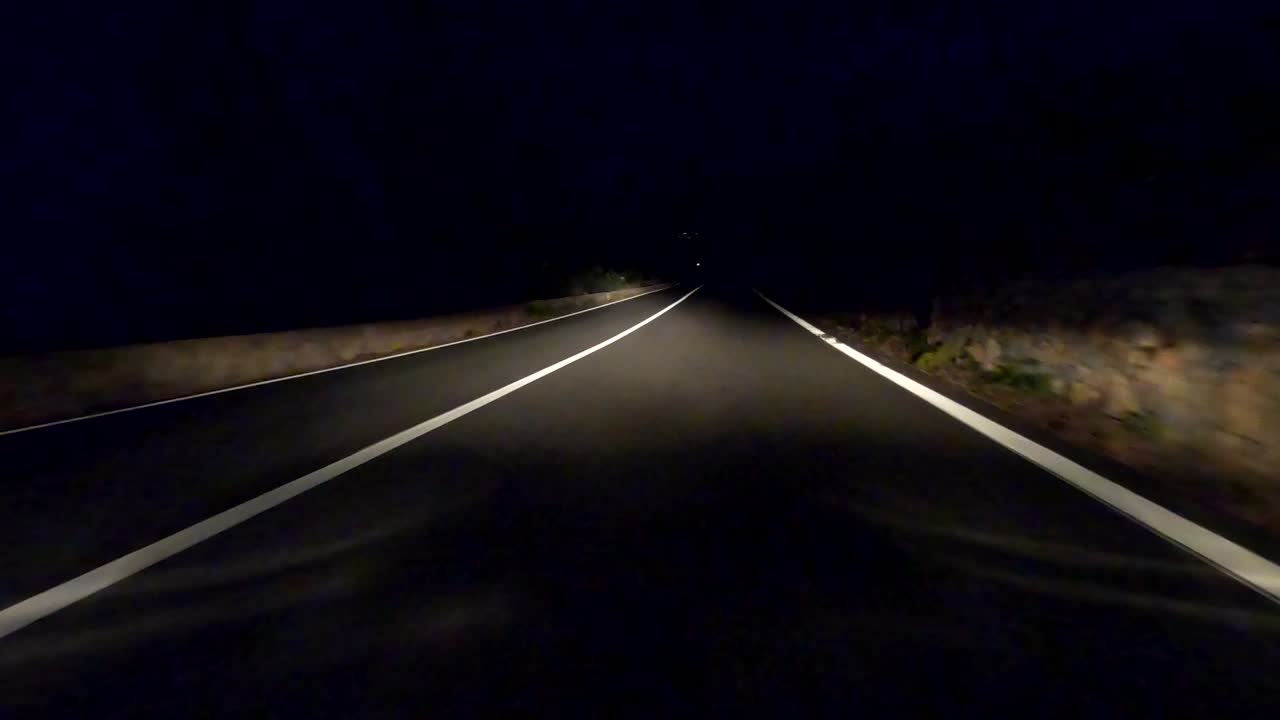 132/5000Video di un viaggio in auto di notte su una strada di montagna con un primo piano sull'asfalto della strada