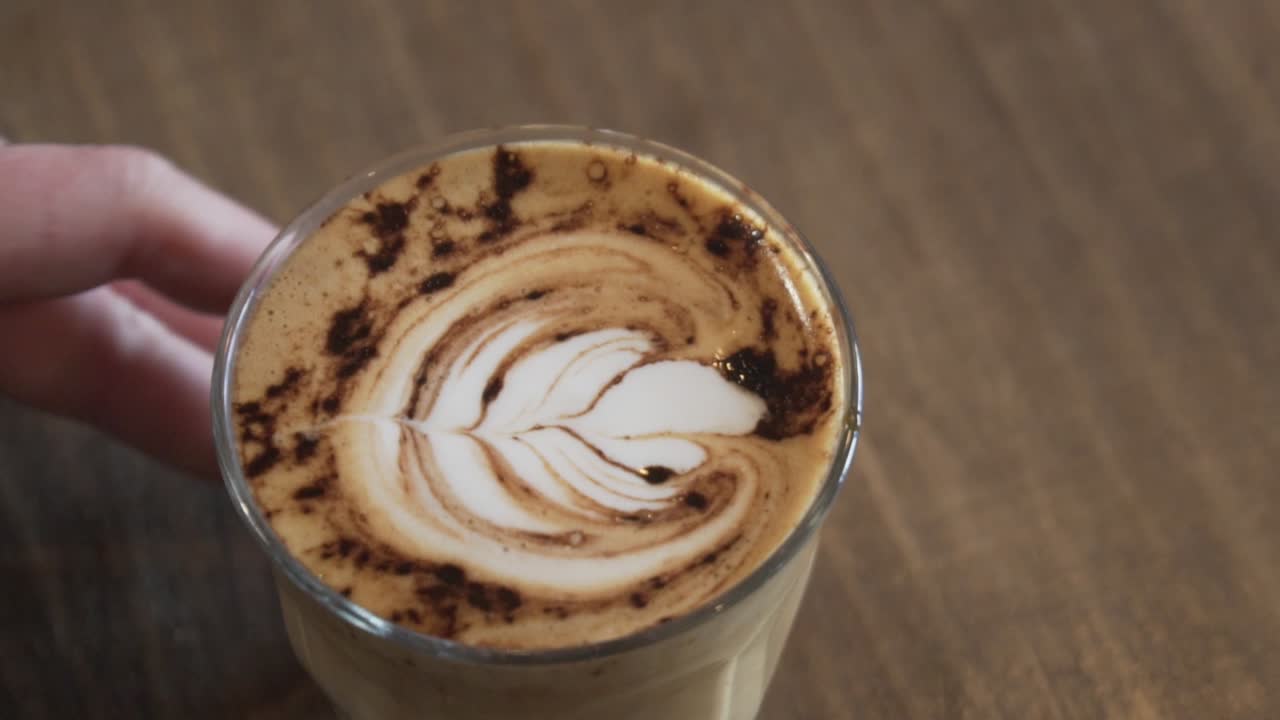 barista che serve un bicchiere di caffè appena fatto con latte art e cannella in cima