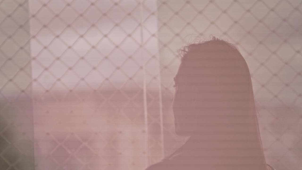 mujer morena relajándose, admirando la vista frente a la ventana del apartamento por la noche