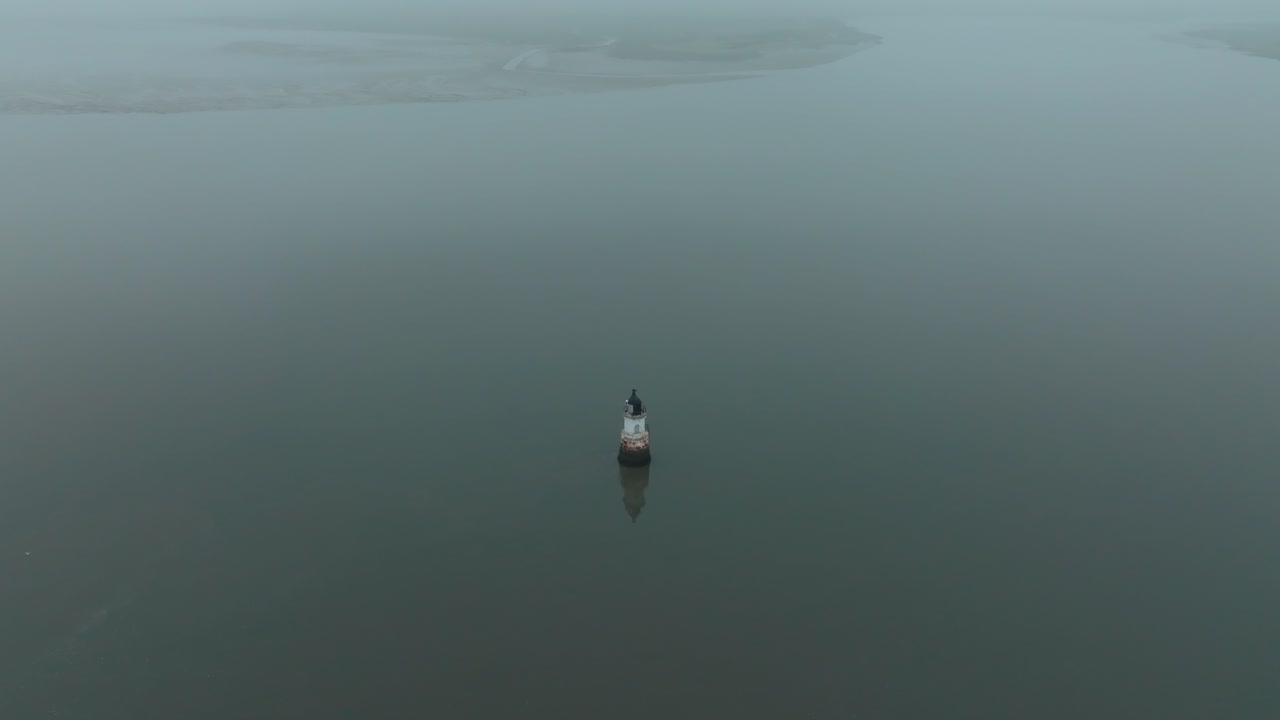 Fast Pullback And Rise From Rusted Derelict Lighthouse In Calm Water On Misty Evening. Pullback showing desolation scale. Plover Scar Lighthouse, Lancashire, UK