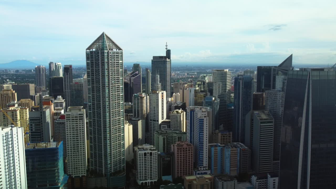 Drone tilting toward skyscrapers in the Makati skyline, sunny Manila, Philippines