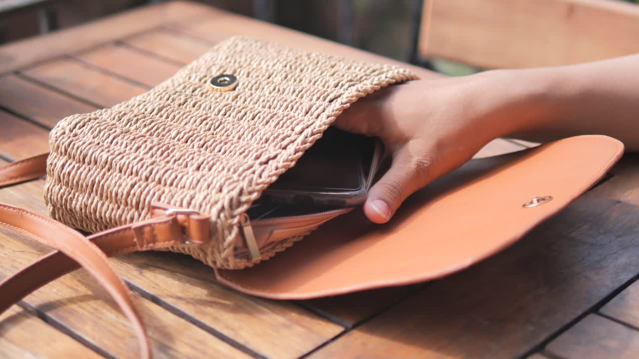 saco de palha da mulher aberto com telefone e carteira dentro