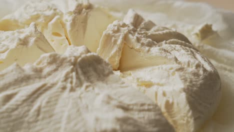 cutting a piece of fresh dairy cream cheese with a small silver knife, closeup