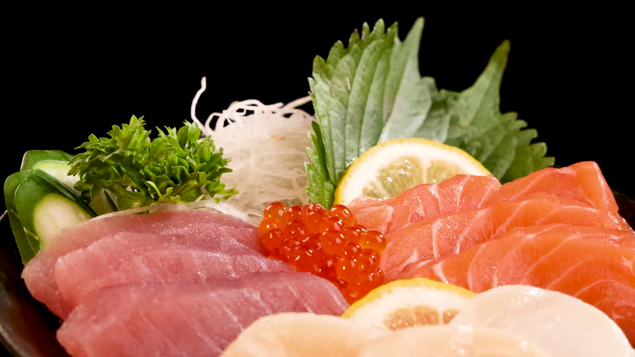 A vibrant platter of salmon, tuna, scallop sashimi, and salmon roe rotates smoothly under bright studio lighting, highlighting fresh textures and colorful garnishes