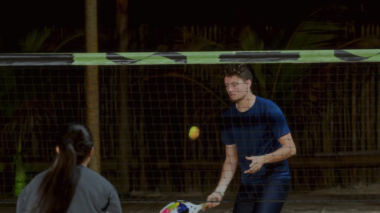 People playing beach tennis at night