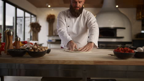 pastry cook hands knead pizza dough in restaurant kitchen. chef cooking in cafe.