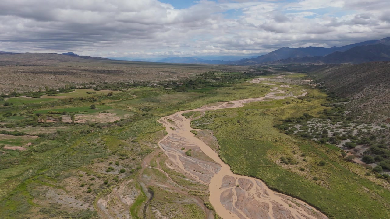 Riprese aeree con drone di un fiume a canali intrecciati che attraversa una valle fertile vicino ai terreni agricoli di Payogasta, sfondo aereo