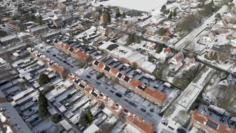 aerial of suburban neighborhood covered in snow with solarpanels on rooftops of houses