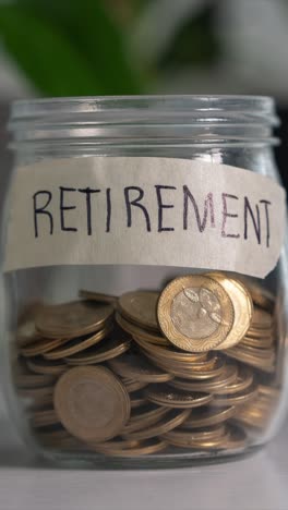 time-lapse saving money for retirement concept. coins into glass jar on desk. vertical