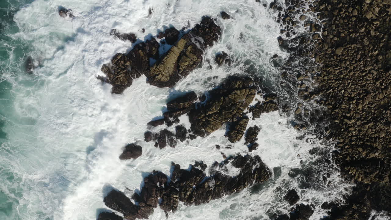 Ripresa drone 4K dall'alto di un'onda enorme che si infrange sulle rocce sulla costa della California.