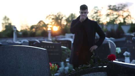 sad man standing in front of a grave during sunset, 4k footage