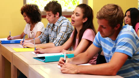 Glückliche-Schüler-Sitzen-In-Einer-Reihe-Und-Hören-Im-Klassenzimmer-Zu