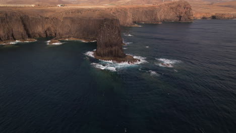 roque partido, gran canaria: aerial view at medium distance and in orbit of the rock formation called roque partido on the island of gran canaria and on a sunny day