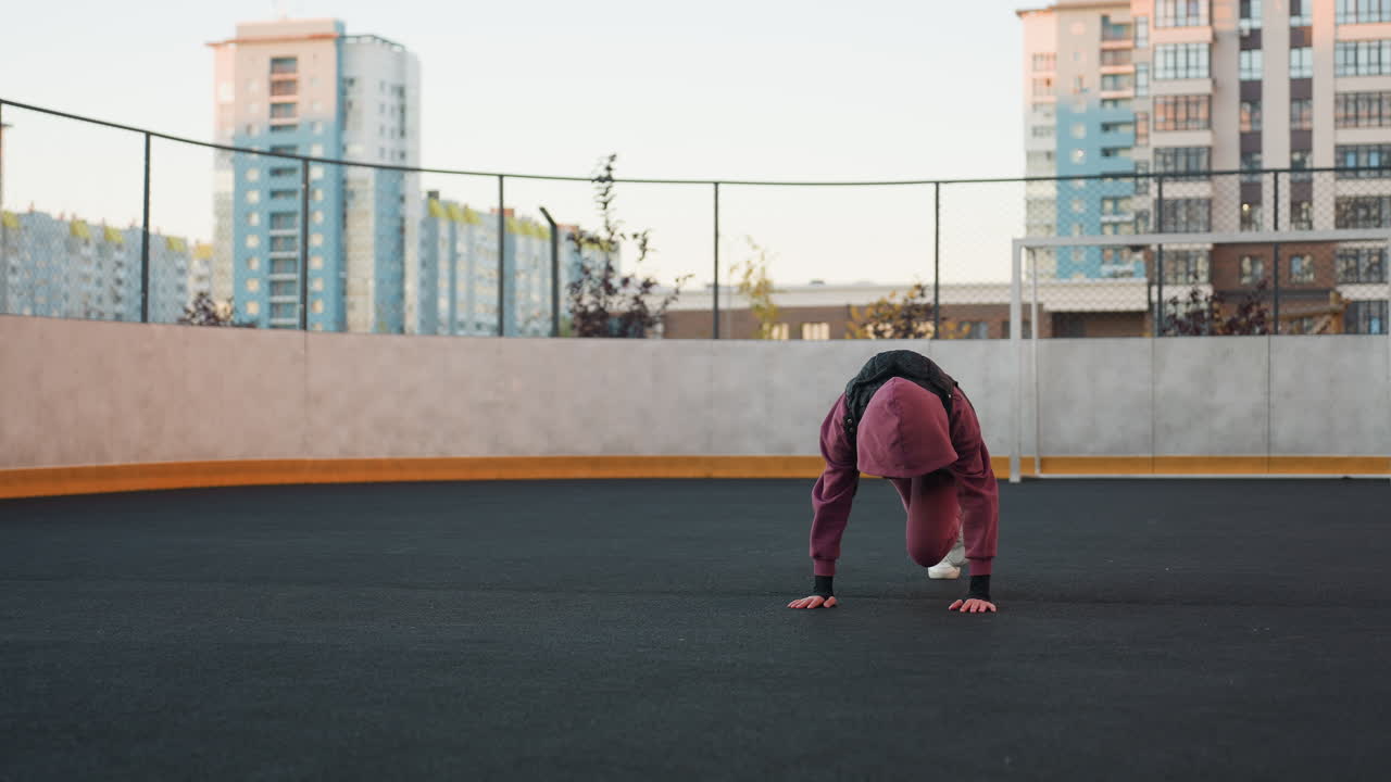 Female fitness enthusiast performing foot crawl exercise with hands on floor moving legs in unison on outdoor urban court under clear sky showcasing core strength coordination and dynamic movement