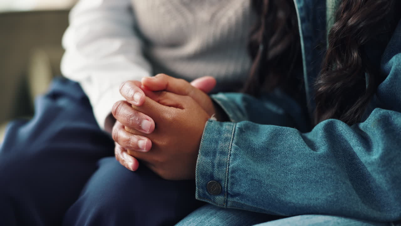 Close-up of two people holding hands in a comforting and supportive gesture