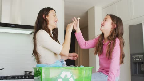 Happy-caucasian-mother-and-daughter-segregating-rubbish,-giving-high-five