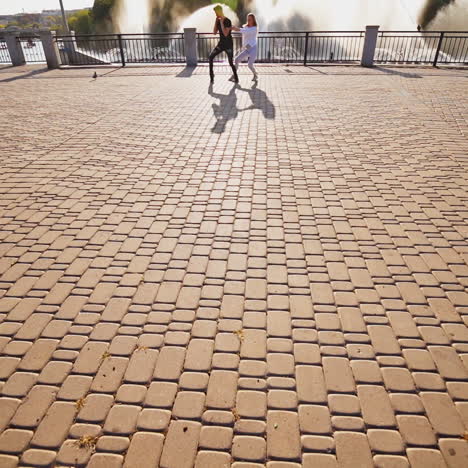 modern dancers are dancing in the street. urban lifestyle. hip-hop generation. boy's and girl's emotional moves on the video. paving stones and young dacing couple at fontain background. aerial view. young beauty dances behind handsome boy.