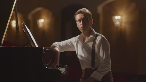 portrait of pianist sitting by grand piano on stage