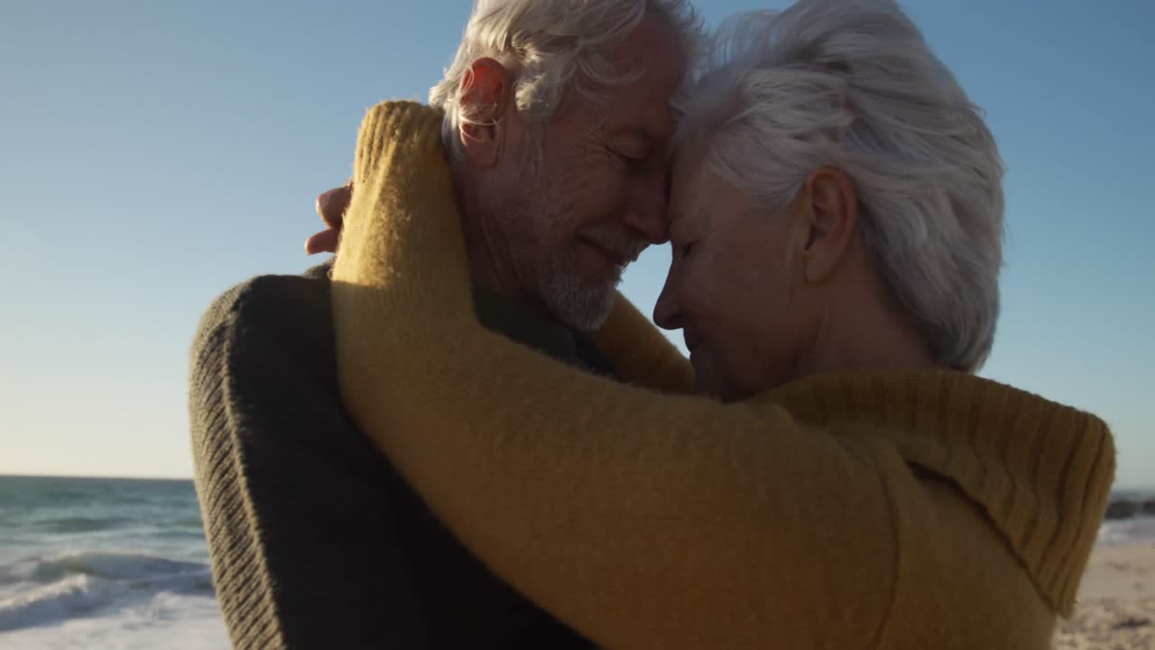 Coppie senior che abbracciano alla spiaggia
