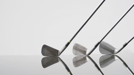 Close-up-of-golf-clubs-on-white-background,-copy-space,-slow-motion